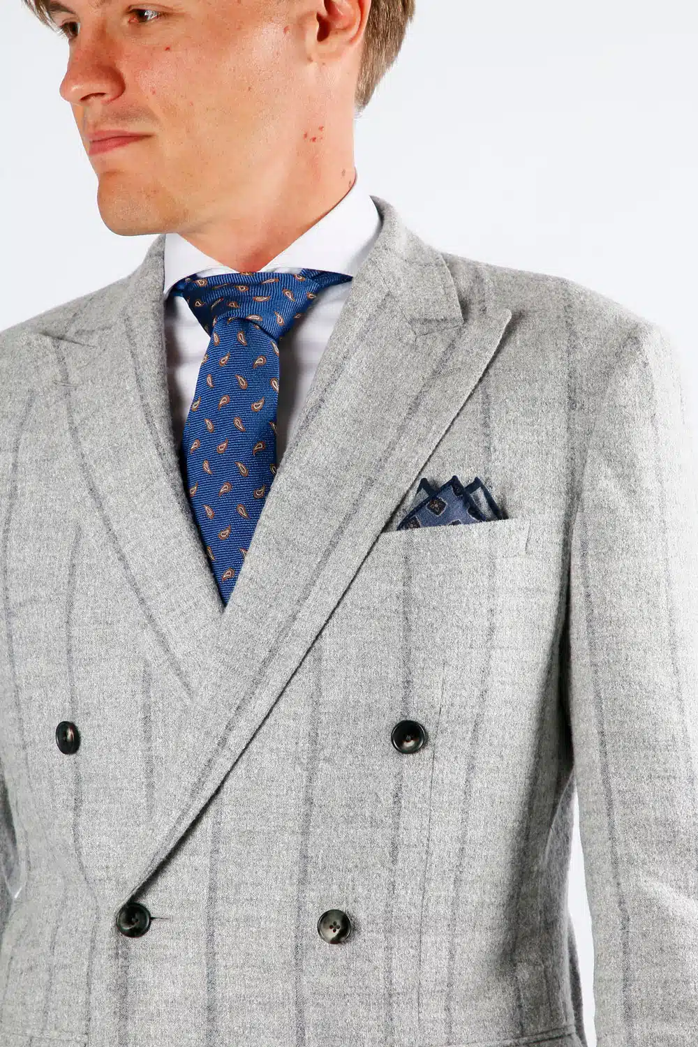 Een grijs gestreept op maat gemaakt doubel breasted pak met blauwe das en passend pochet.